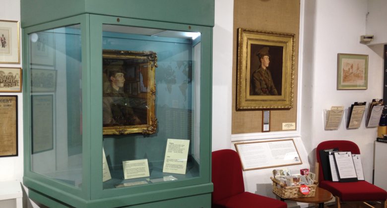 A museum display case displaying paintings of a world war 1 soldier by the artsit Stanhope Forbes