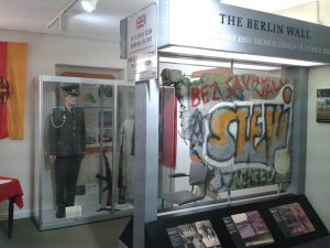 A view of a museum display showing a large section of the Berlin wall, heavy with graffiti