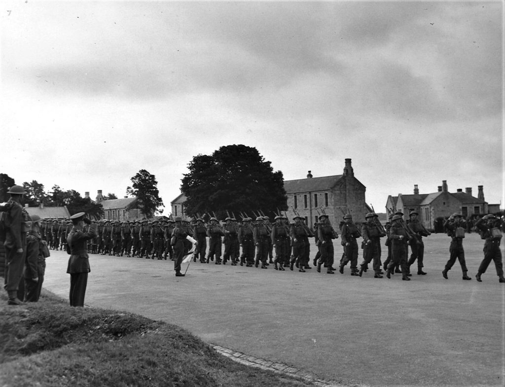 Black and white photograph of troops marching in a line outside Bodmin Barracks.