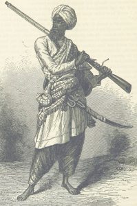 A Sikh soldier standing holding a rifle over his shoulder